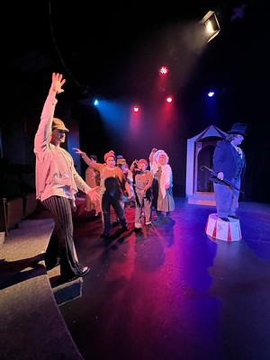 Performers walking on stage during Midsummer Night's Dream performance while a male character stands on a Circus red and white round platform