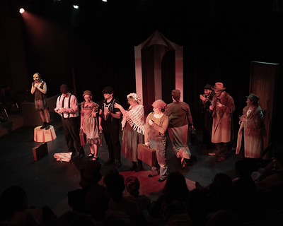 Performers mingle on stage in early 1900's clothing during Midsummer Night's Dream performance while a male character stands on a Circus red and white round platform