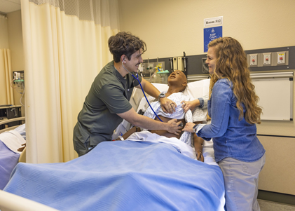 Nursing students listening to simulation doll's breathing with stethoscope